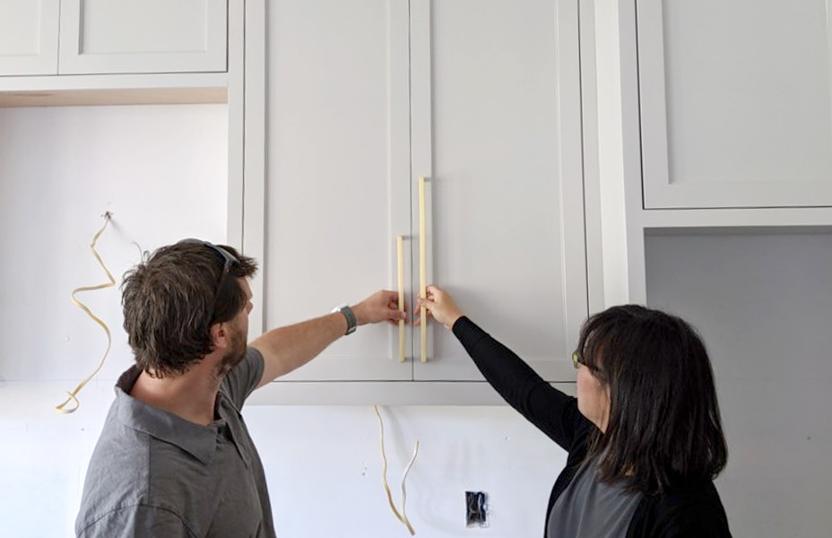 Two people comparing kitchen cabinet handle length