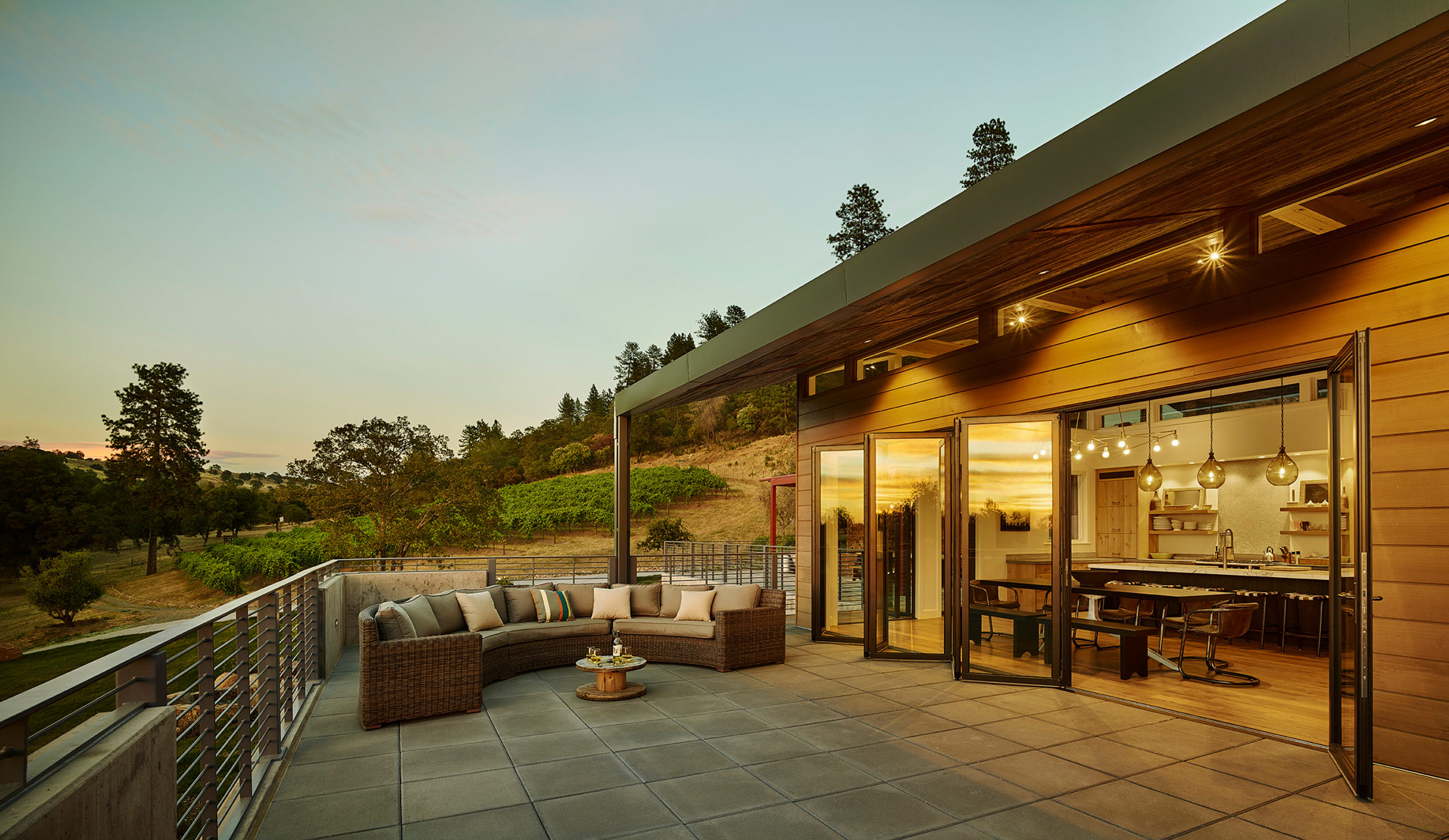 open plan kitchen with accordion door opening to deck with seating and vineyard in the background